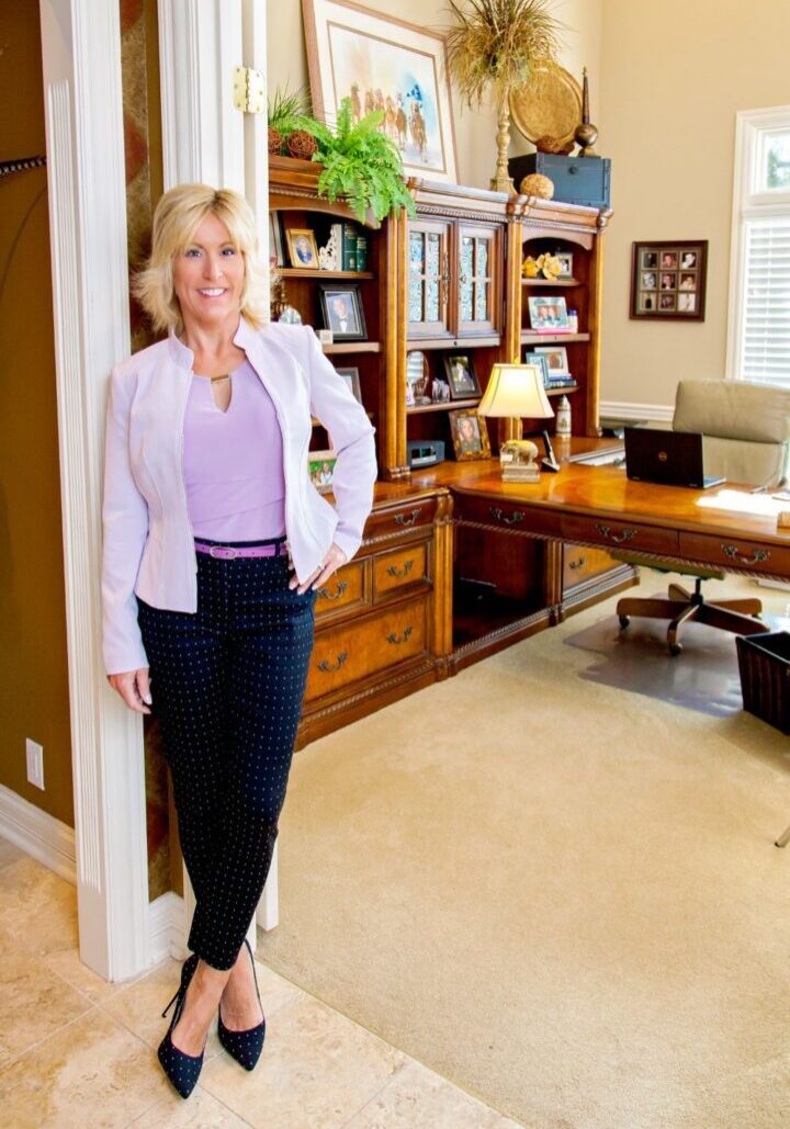 A woman standing in her home office with a desk.
